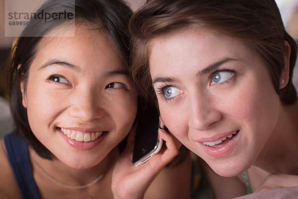 Zwei junge Frauen  die zusammen Handy hören