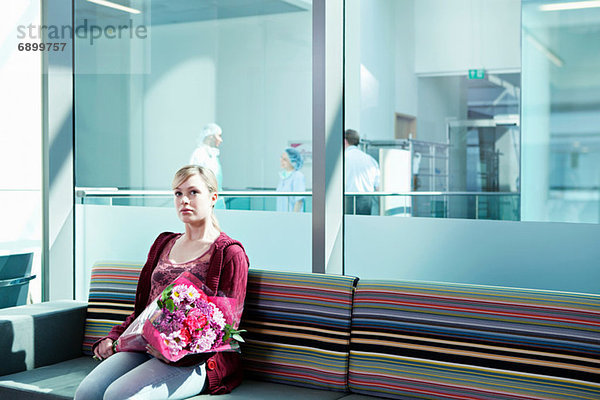 Frau im Wartezimmer des Krankenhauses mit Blumenstrauß
