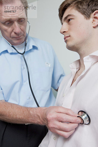 Arzt mit Stethoskop am Patienten während der ärztlichen Untersuchung