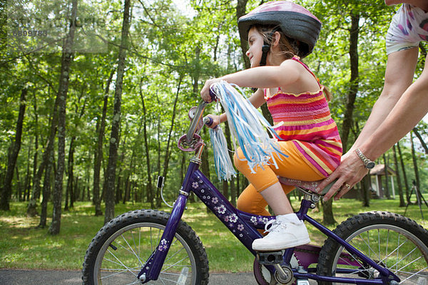 Mutter hilft Tochter beim Radfahren