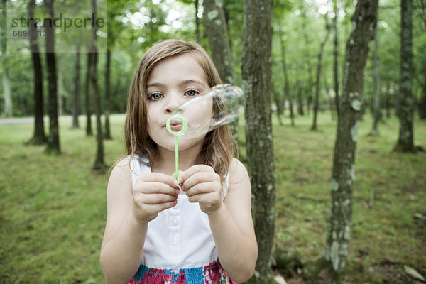 Mädchen bläst Blasen im Wald
