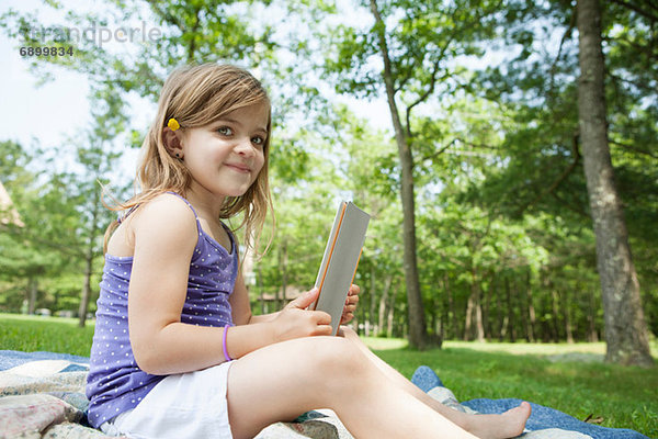 Mädchen sitzend auf Picknickdecke mit digitalem Tablett