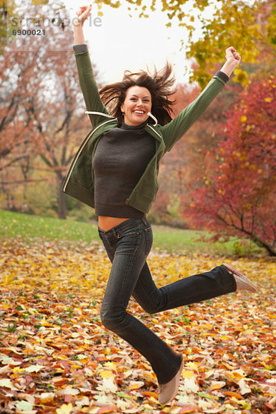 Frau beim Springen im Herbstlaub