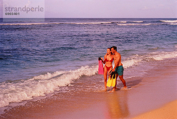 Couple in Swimwear  Walking on Beach Holding Flippers