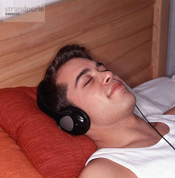 Man Lying on Bed  Using Headphones