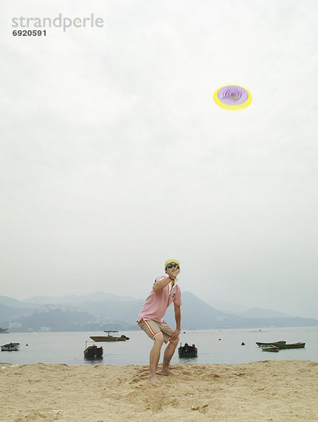 Mann spielen Frisbee am Strand