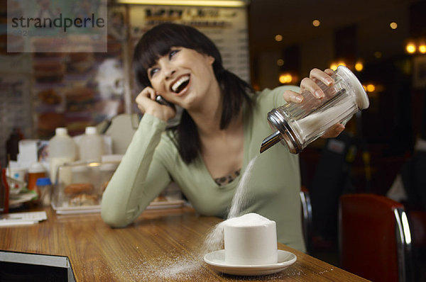 Woman Distracted by Phone Call  Filling Cup with Sugar