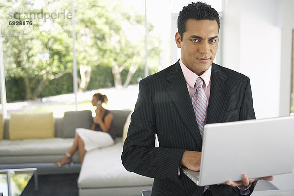 Businessman Holding Laptop  Woman in Background