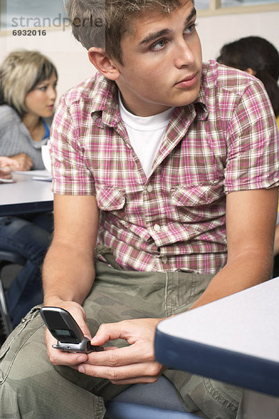 Student mit Handy im Klassenzimmer