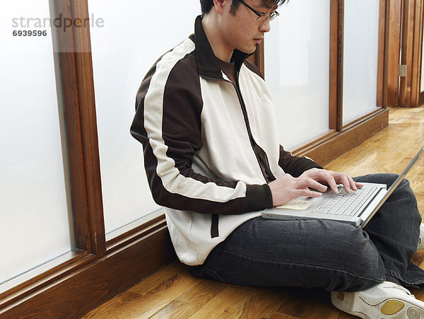 Mann sitzen auf Boden mit Laptop
