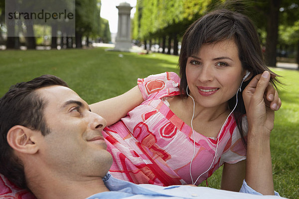 Couple Lying on Grass  Woman Listening to Mp3 Player