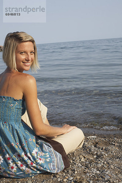 Frau sitzt am Strand