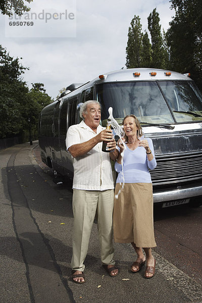 Couple Standing by Trailer  Celebrating With Champagne