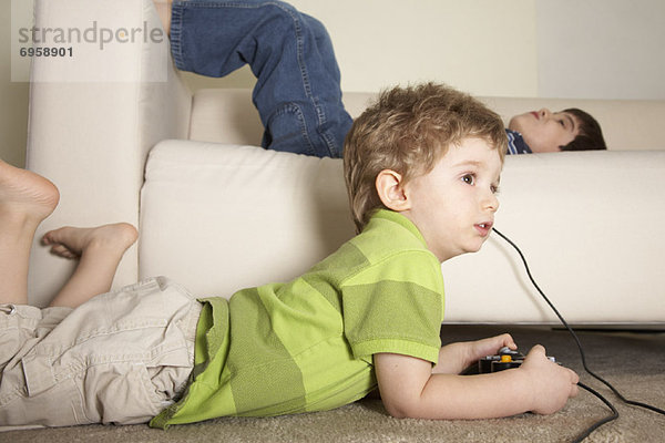 Boy Playing Video Games  Brother Lying on Sofa