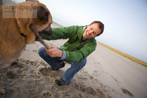 Mann mit Hund am Strand