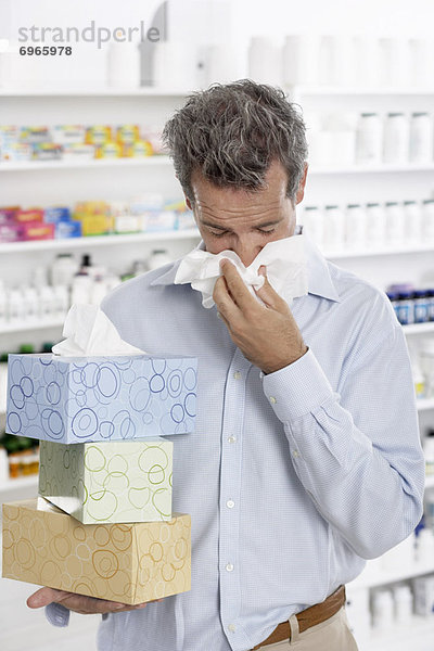 Man in Pharmacy Blowing Nose  Carrying Boxes of Tissue