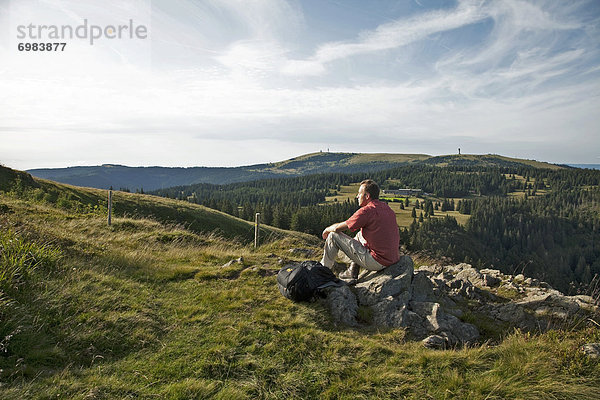 Einzelner Wanderer auf dem Herzogenhorn genießt den Ausblick zum Feldberg im Schwarzwald  Baden-Württemberg  Deutschland  Europa