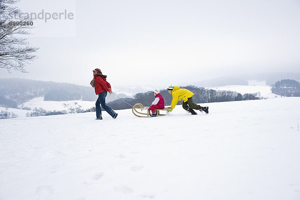 Mother Pulling Daughter in Sled  Son Pushing Sled from Behind