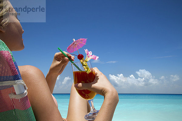 Frau mit tropischem Getränk am Strand