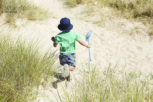 Junge mit Fischernetz am Strand