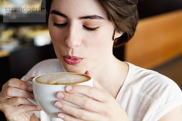 Frau bläst auf Kaffee im Cafe