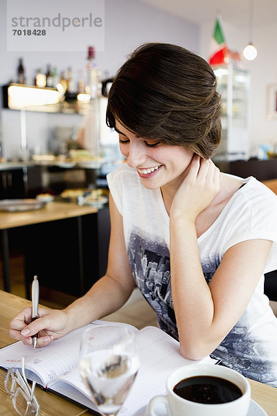 Lächelnde Frau beim Schreiben im Café