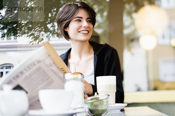 Frau liest Zeitung im Café