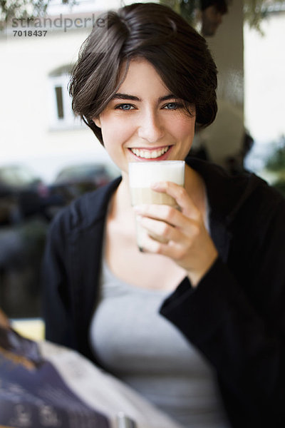 Lächelnde Frau trinkt Kaffee im Café