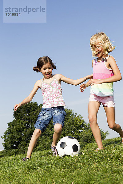 Mädchen spielen Fußball im Feld