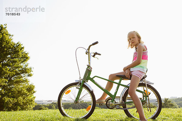 Mädchen auf dem Fahrrad im Gras sitzend