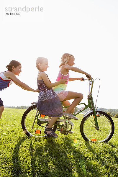 Mädchen spielen mit dem Fahrrad im Gras