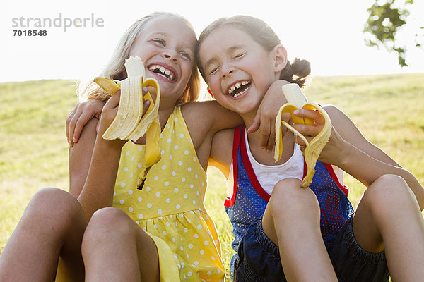 Lachende Mädchen beim Bananenessen im Freien