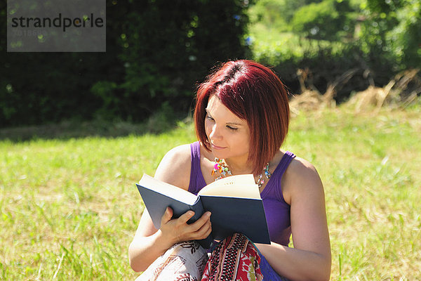 Frau liest Buch im Gras