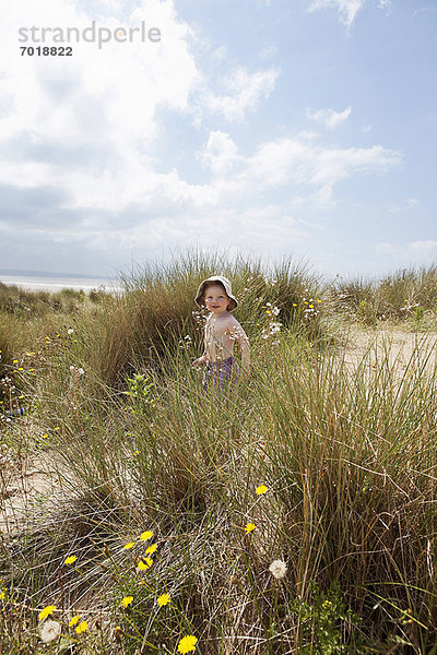 Junge  der im grasbewachsenen Sand läuft