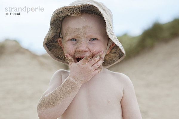 Junge mit Sand bedeckt am Strand