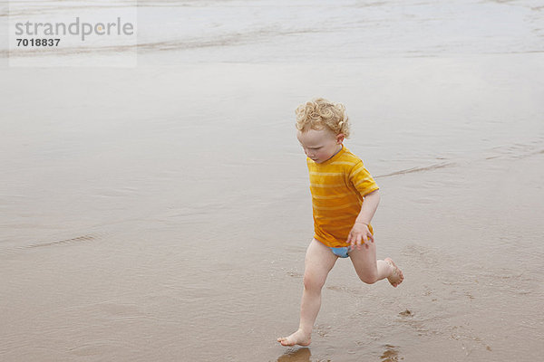 Junge läuft in Wellen am Strand