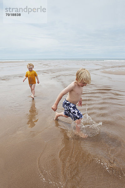 Kinder spielen in Wellen am Strand