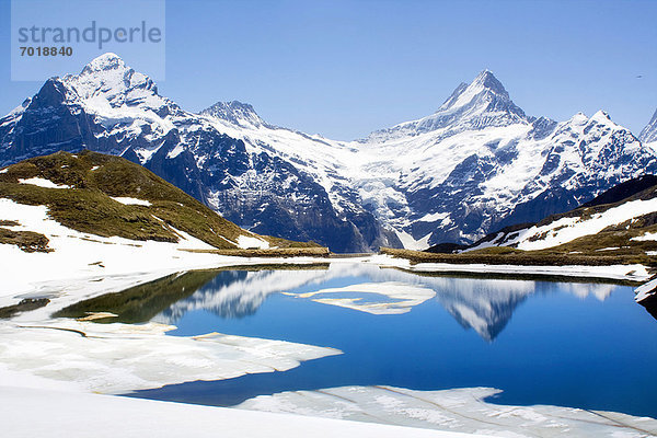 Schneelandschaft spiegelt sich im stillen See wider