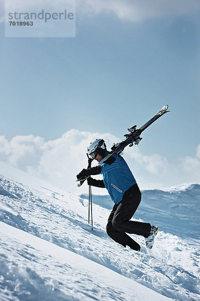 Skifahrer klettert auf verschneite Berghänge