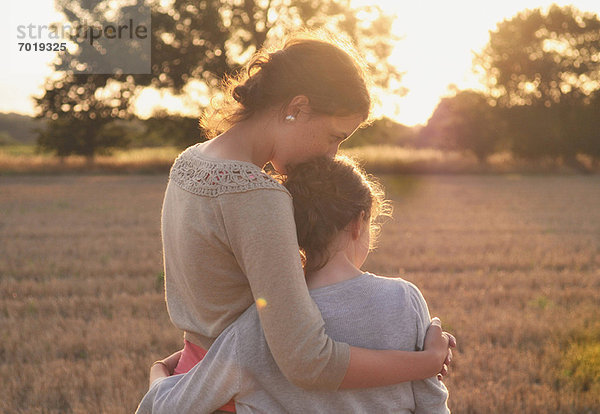 Mutter und Tochter umarmen sich im Feld