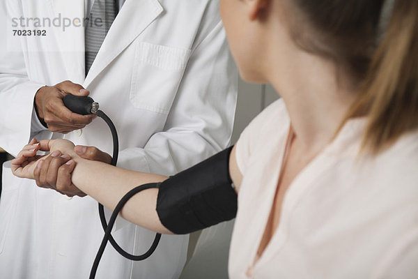 Arzt kontrolliert den Blutdruck des Patienten  abgeschnitten
