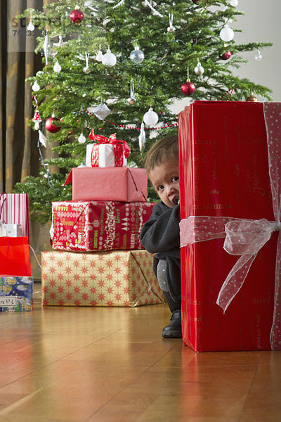 Kleines Mädchen versteckt sich hinter einem Weihnachtsgeschenk