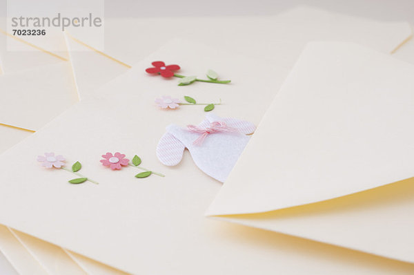 Briefpapier verziert mit Miniatur-Babykleidung und Blumen
