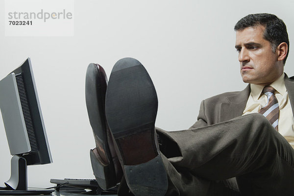 Geschäftsmann sitzend im Büro mit Füßen auf dem Schreibtisch