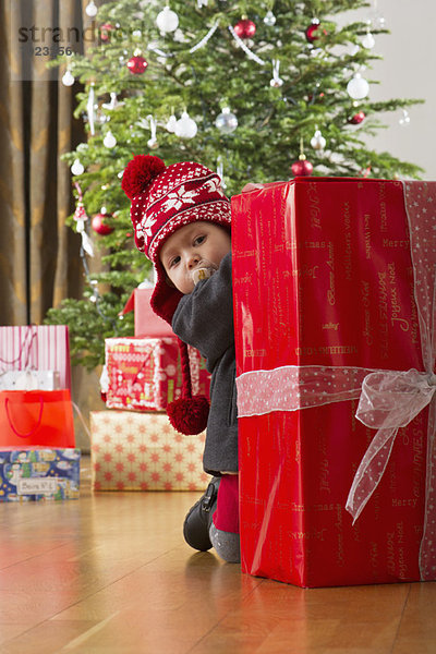 Kleines Mädchen schaut auf großes Weihnachtsgeschenk