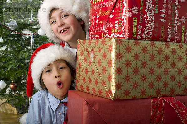 Jungen  die sich in einem Stapel Weihnachtsgeschenke umsehen.