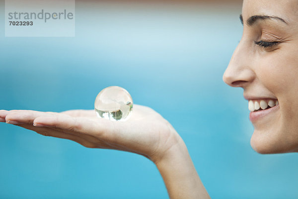 Junge Frau mit Kristallkugel in der Handfläche  Seitenansicht