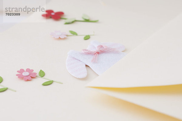 Briefpapier verziert mit Miniatur-Babykleidung und Blumen
