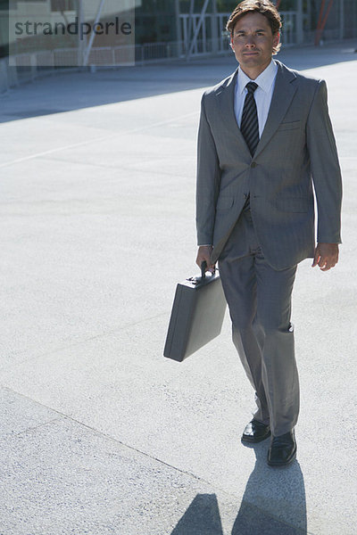 Geschäftsmann beim Spaziergang im Freien mit Aktentasche in der Hand