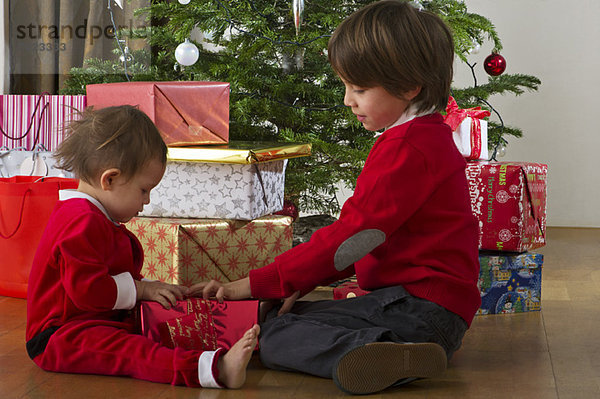 Junge Geschwister eröffnen gemeinsam Weihnachtsgeschenk